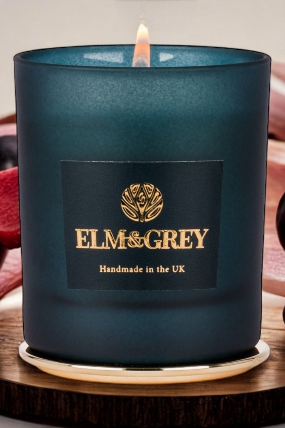 Elm & Grey candle on a wooden coaster with a blurred background