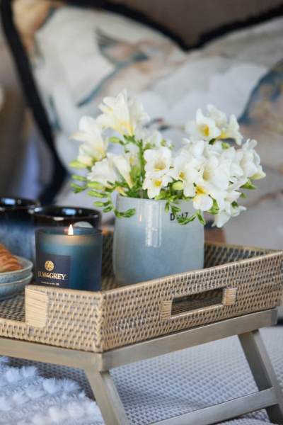 Candle and flowers on a wicker tray with a blurred background
