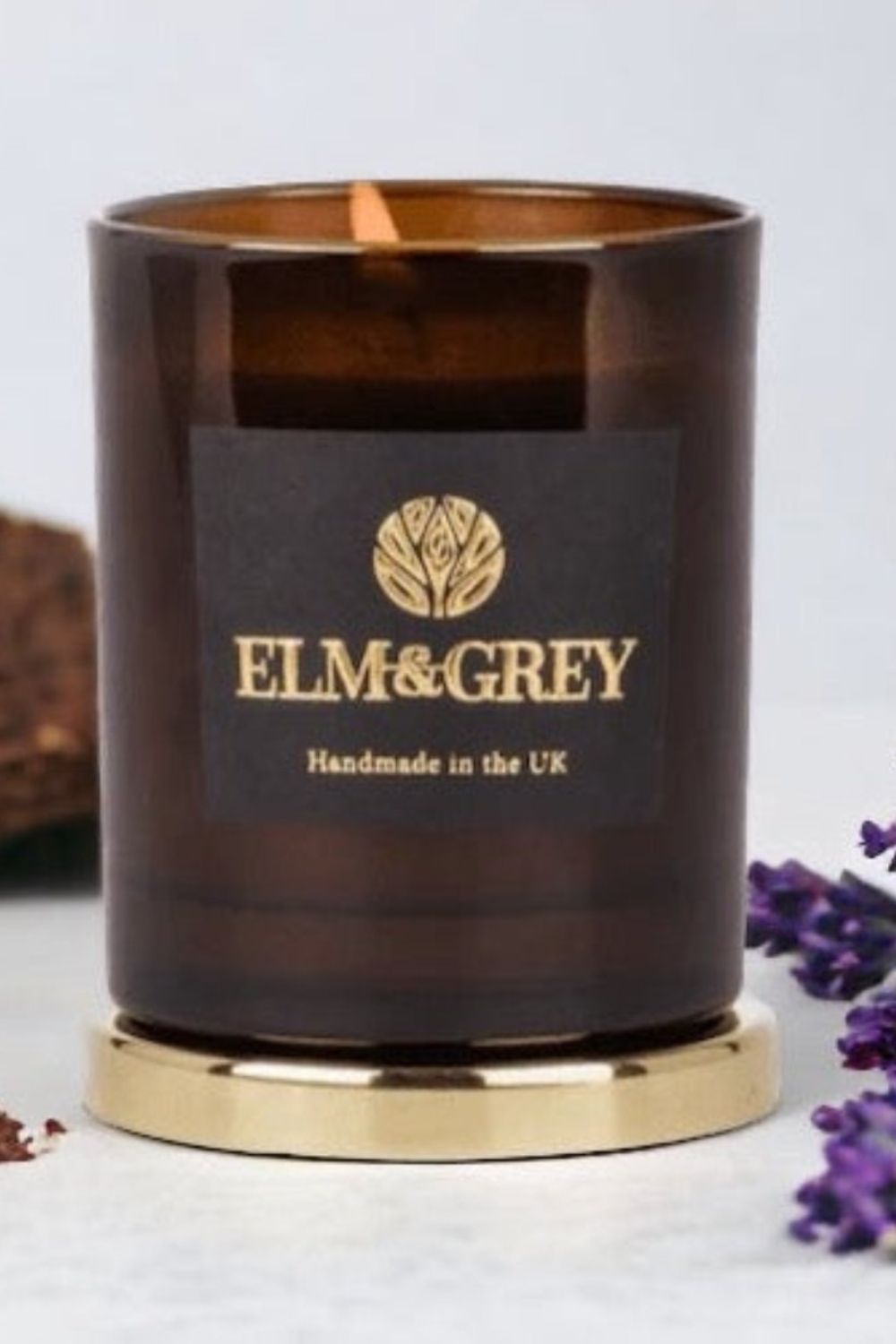 Brown candle with gold base and 'Elm & Grey' label on a light background