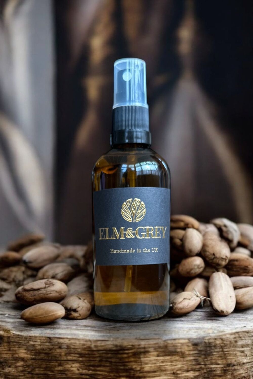 Bottle of Elm & Grey room spray product with tonka beans in the background