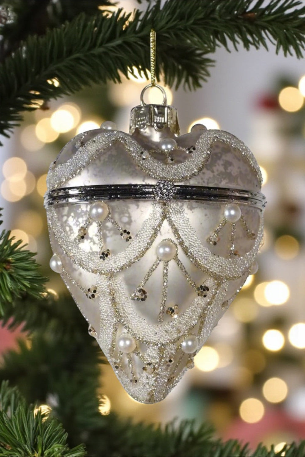 Decorative heart-shaped ornament on a Christmas tree with blurred lights in the background