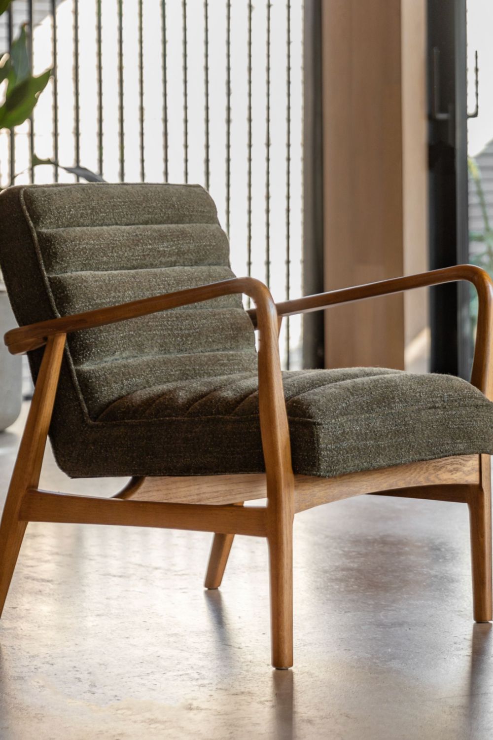 Green armchair with wooden frame on a wooden floor