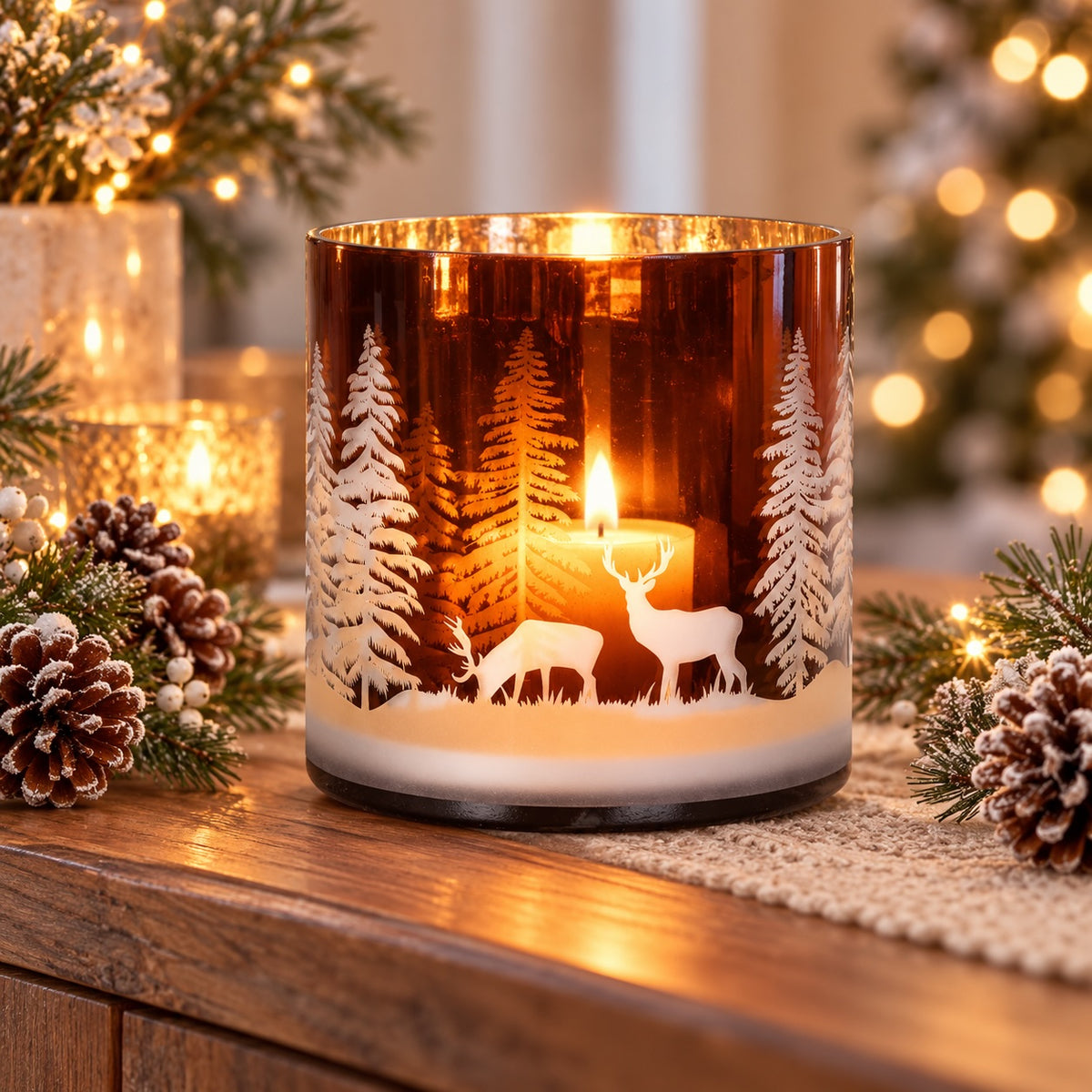 Large Amber Forest glass candle holder glowing in a warm winter setting styled with pinecones