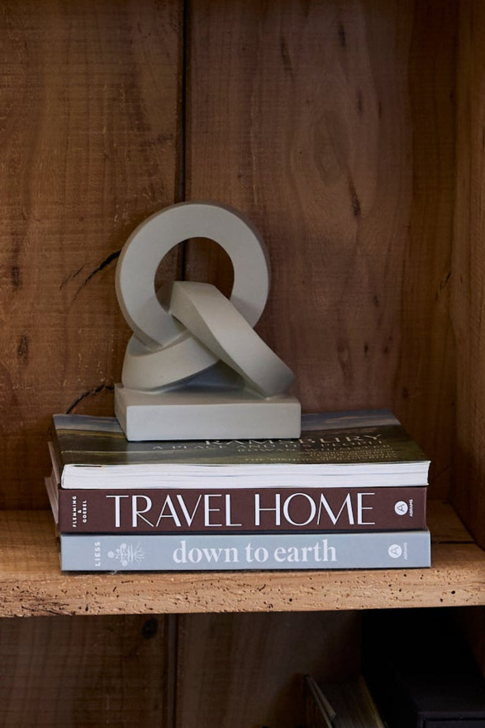 grey resin knot resting on a pile of books in a rustic book case