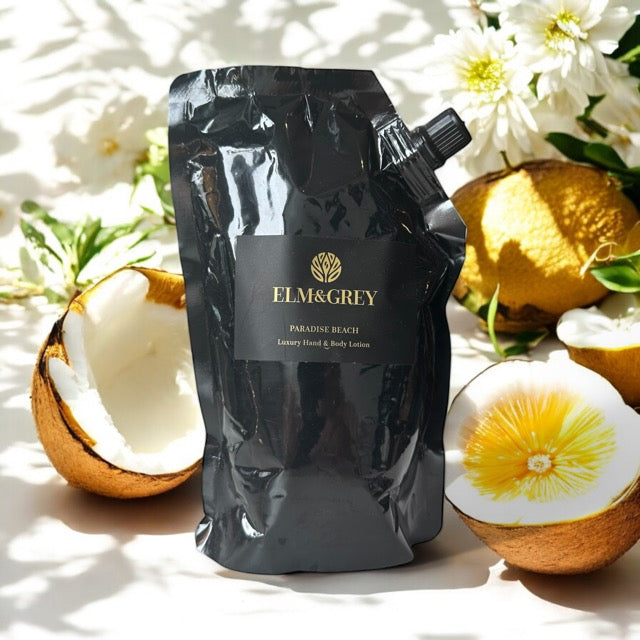 Elm & Grey Paradise Beach Luxury Hand & Body Lotion 450ml Black Refill Pouch sitting on a surface with Coconut Citrus and Florals in the background