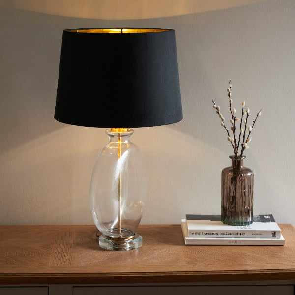 Black shade on a clear glass table lamp base on a side board
