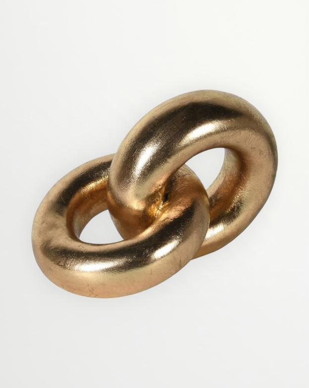 A metallic gold decorative sculpture resembling two interlocking links or rings, photographed on a clean white background.