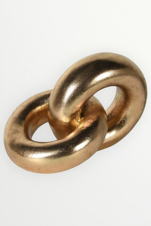 A metallic gold decorative sculpture resembling two interlocking links or rings, photographed on a clean white background.