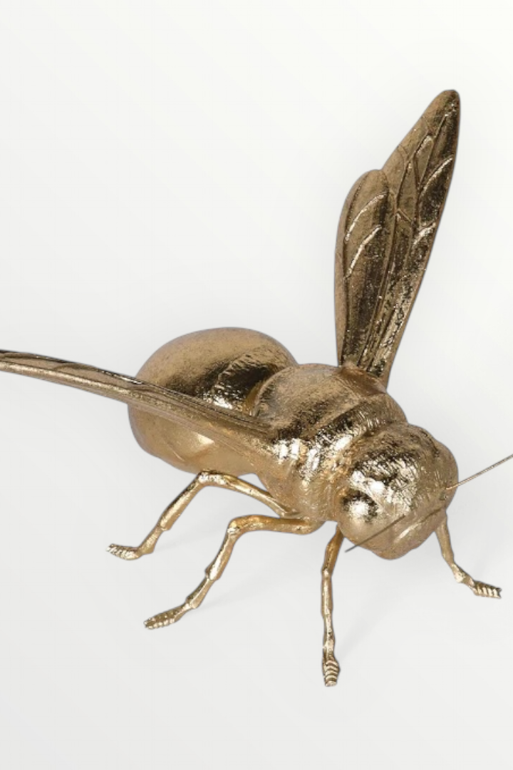 A decorative gold bee ornament with intricate detailing on a white background.