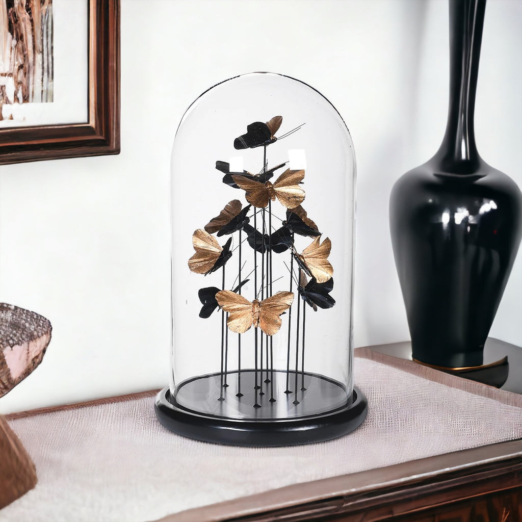 Golden butterflies in a glass dome sitting on a side board 