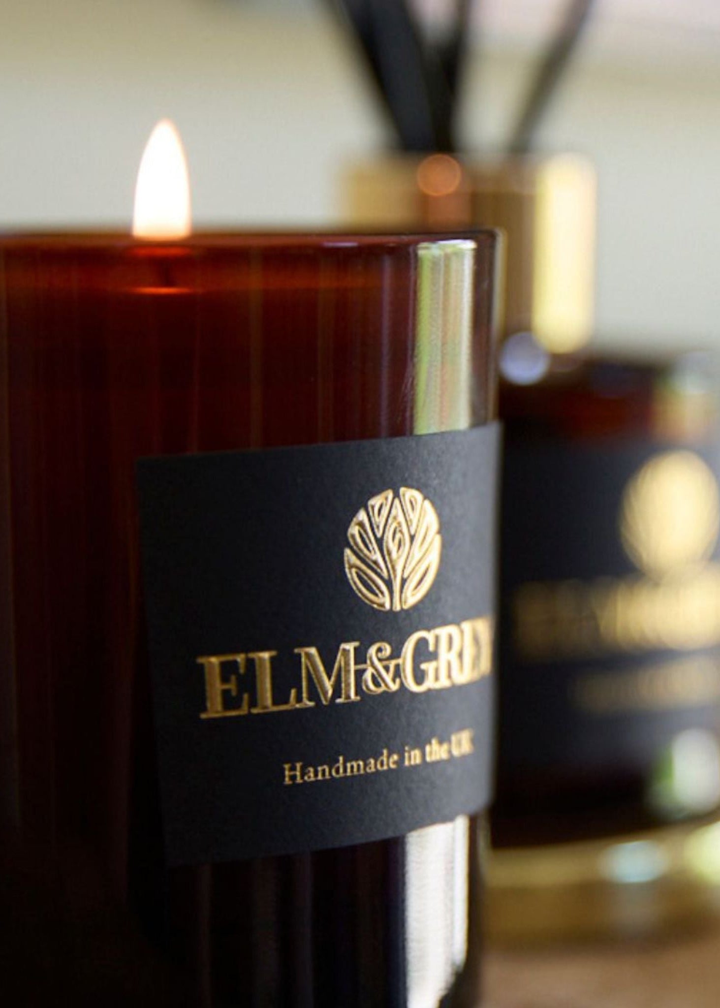 Candle with 'Elm & Grey' label in focus, blurred background