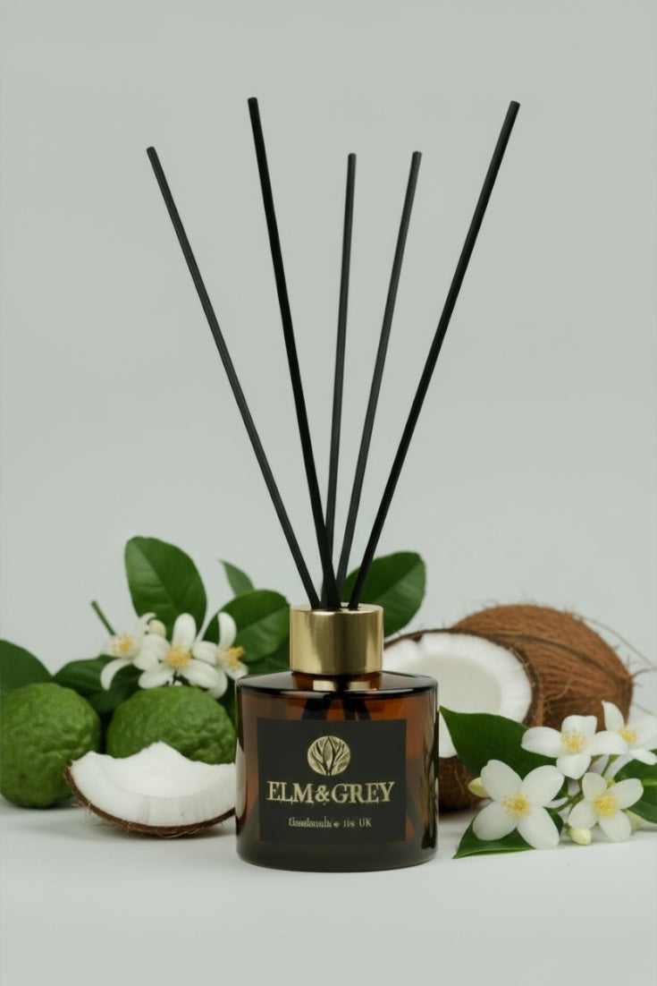 Reed diffuser with black sticks, coconut, and flowers on a light grey background