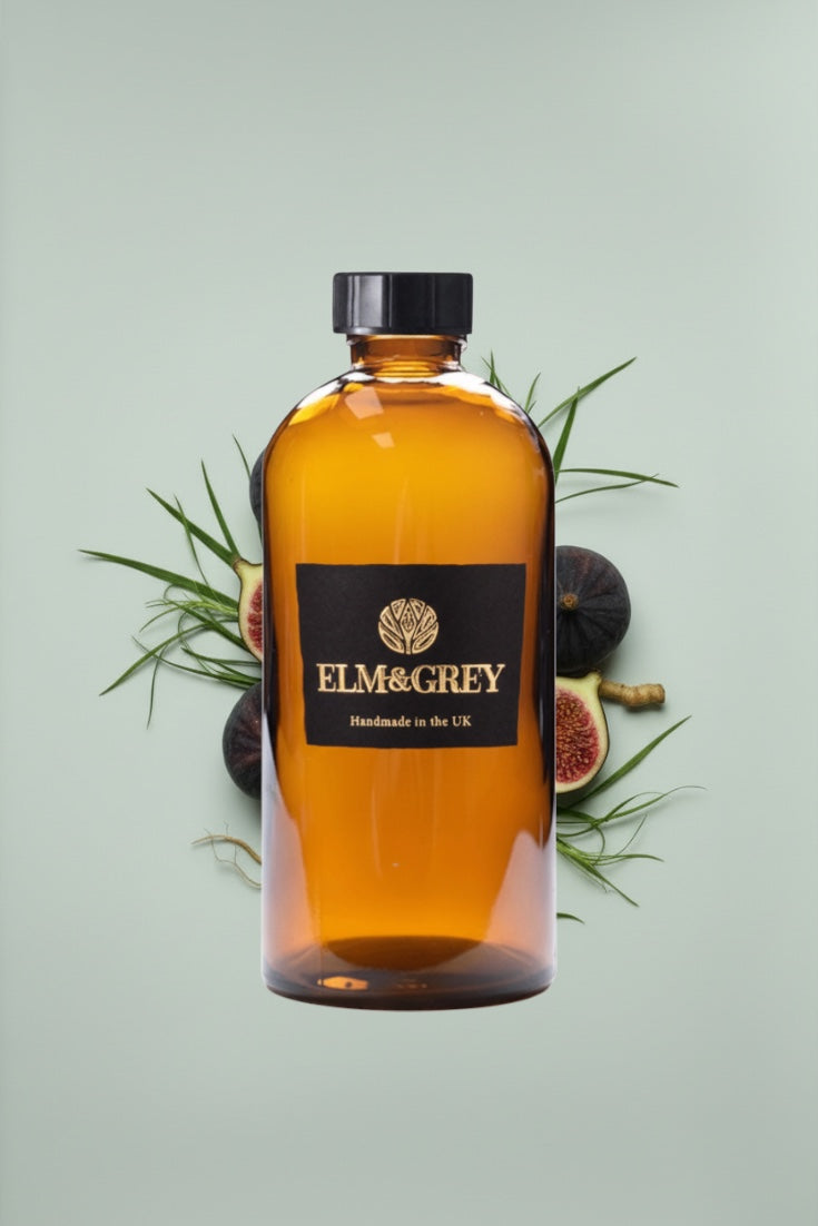 Bottle of Elm & Grey diffuser refill liquid on a light green background with figs and leaves.