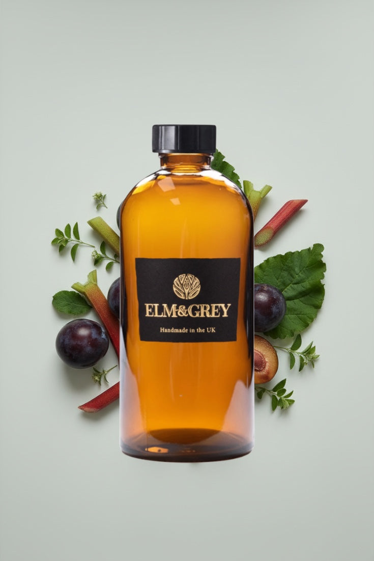 Bottle of Elm & Grey diffuser refill liquid surrounded by fruits and leaves on a light background