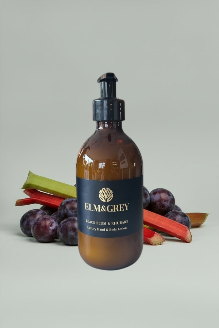 Amber bottle of Elm & Grey hand and body lotion with black plum and rhubarb on a light gray background