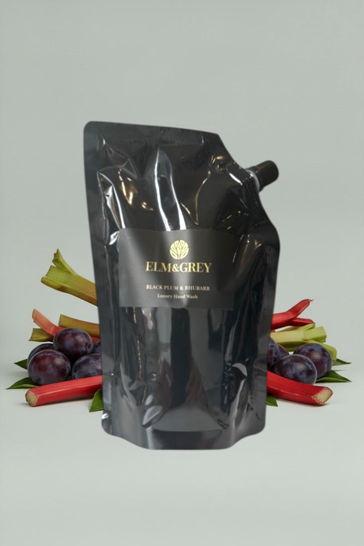 Black pouch with 'Elm & Grey' branding on a grey background with plums and rhubarb.
