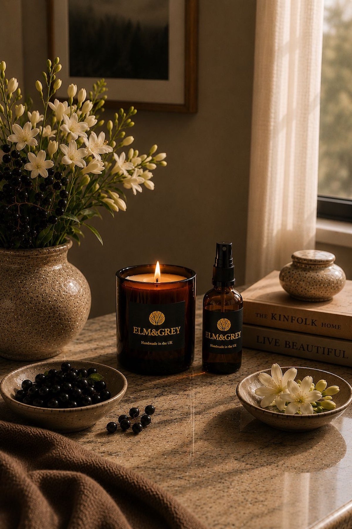 Elm & Grey Blackcurrant and Tuberose scented candle and room spray styled with white tuberose, blackcurrants and Kinfolk books in warm evening light