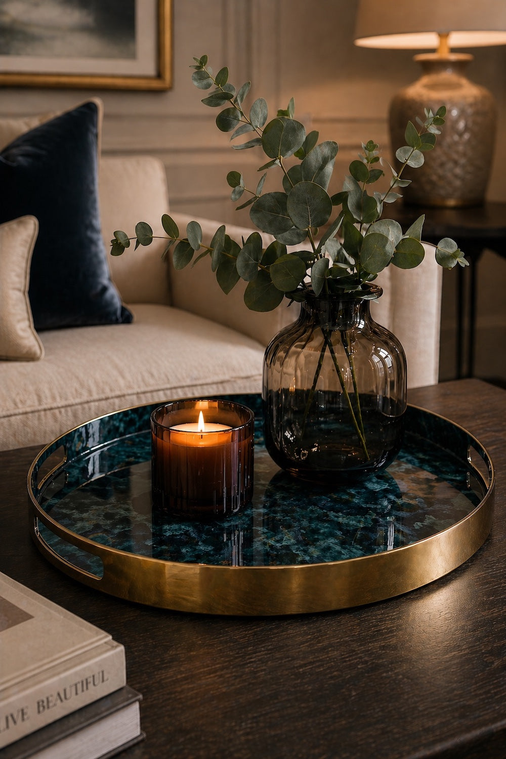 Round blue marble-effect decorative tray with gold brass rim and handles styled with eucalyptus and lit tealight on a dark wood coffee table — Elm & Grey