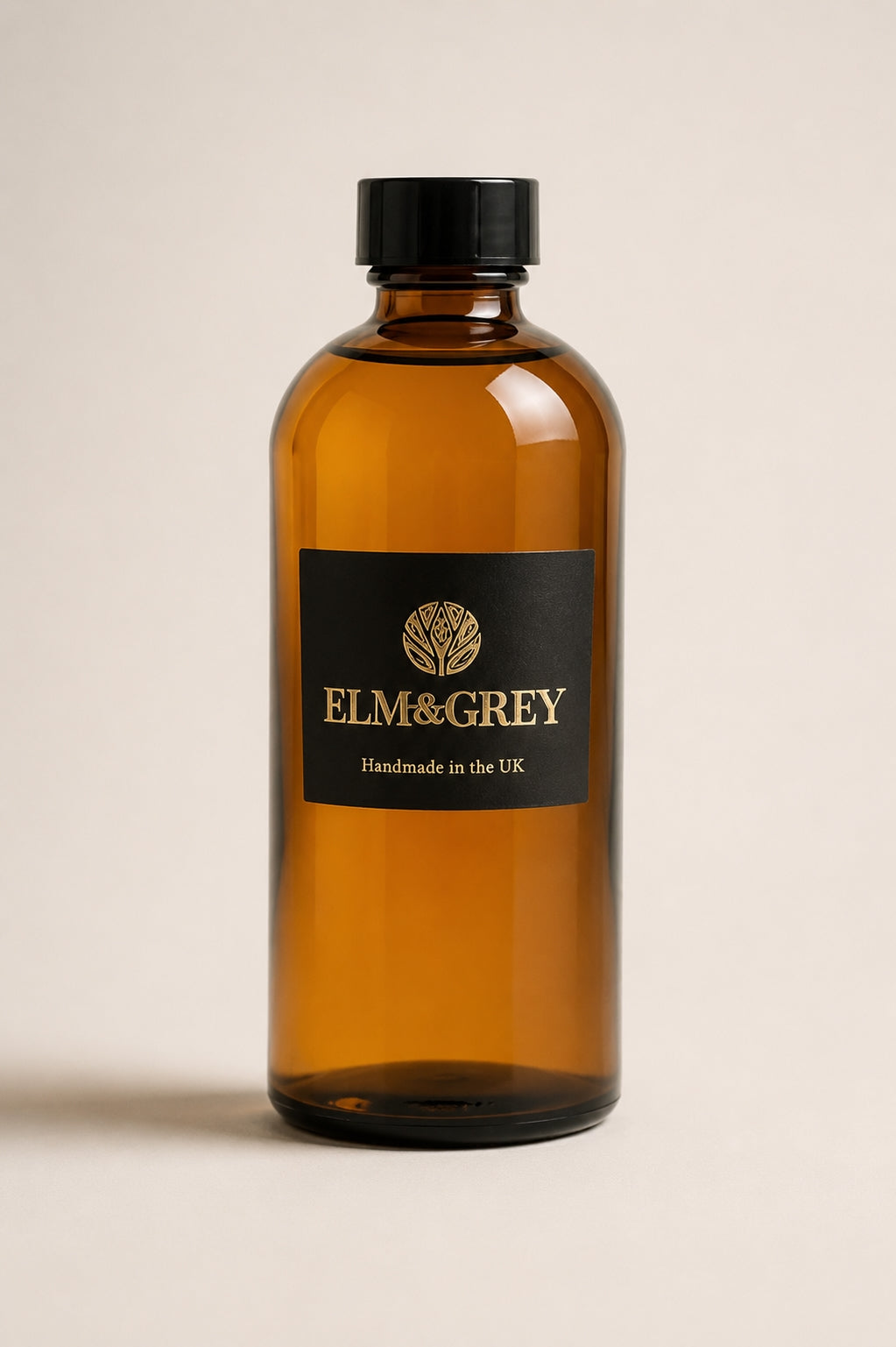 Amber glass reed diffuser refill bottle with black cap by Elm & Grey on a beige background