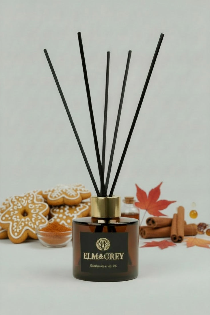 Reed diffuser with black sticks and 'Elm & Grey' branding on a light background with autumn elements.
