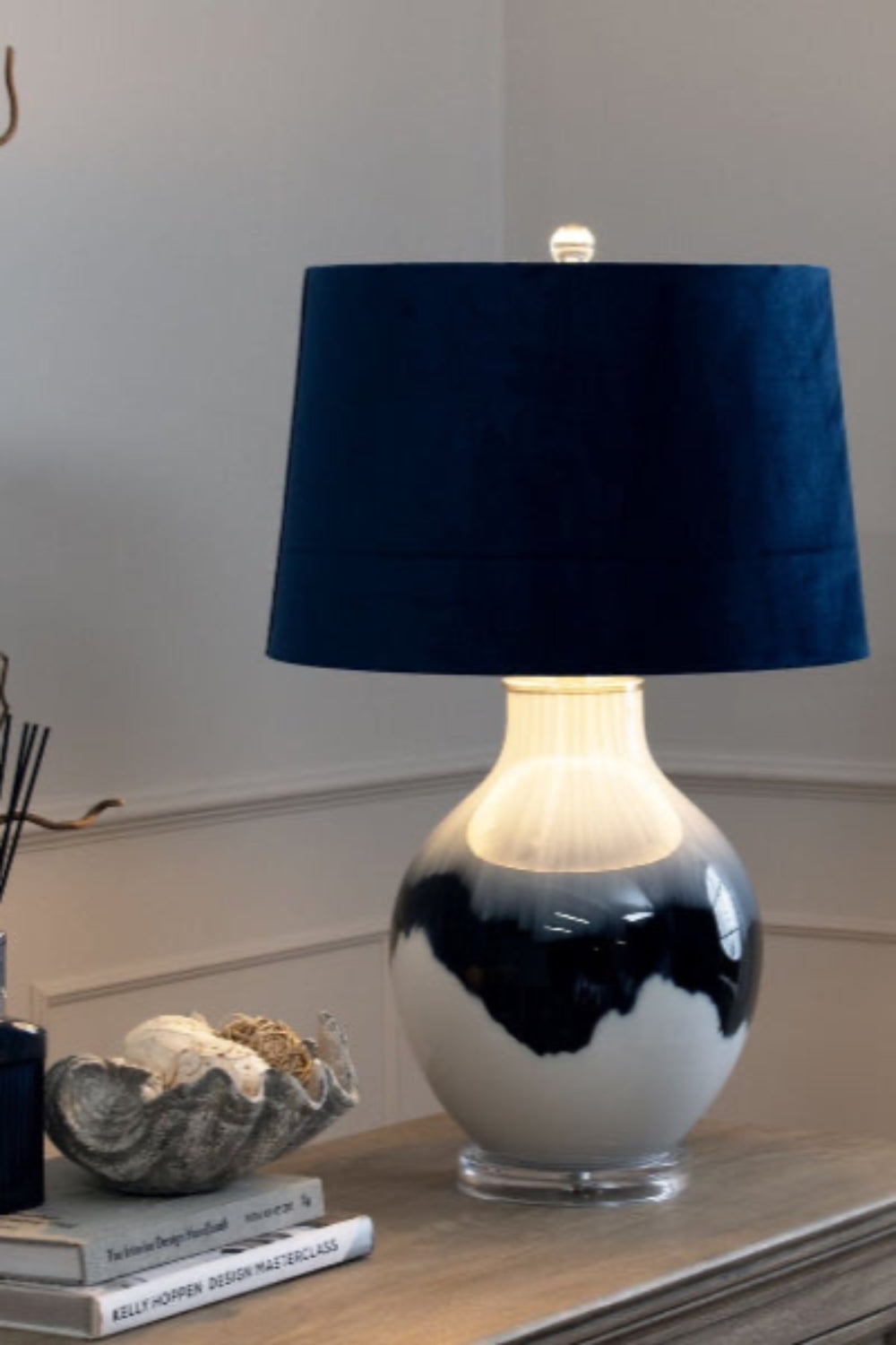 Table lamp with a blue shade and blue and white base on a surface. Elm & Grey.