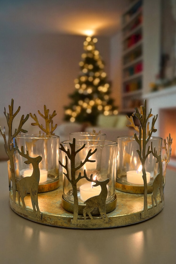 Decorative candle holder with deer and tree designs in front of a Christmas tree.