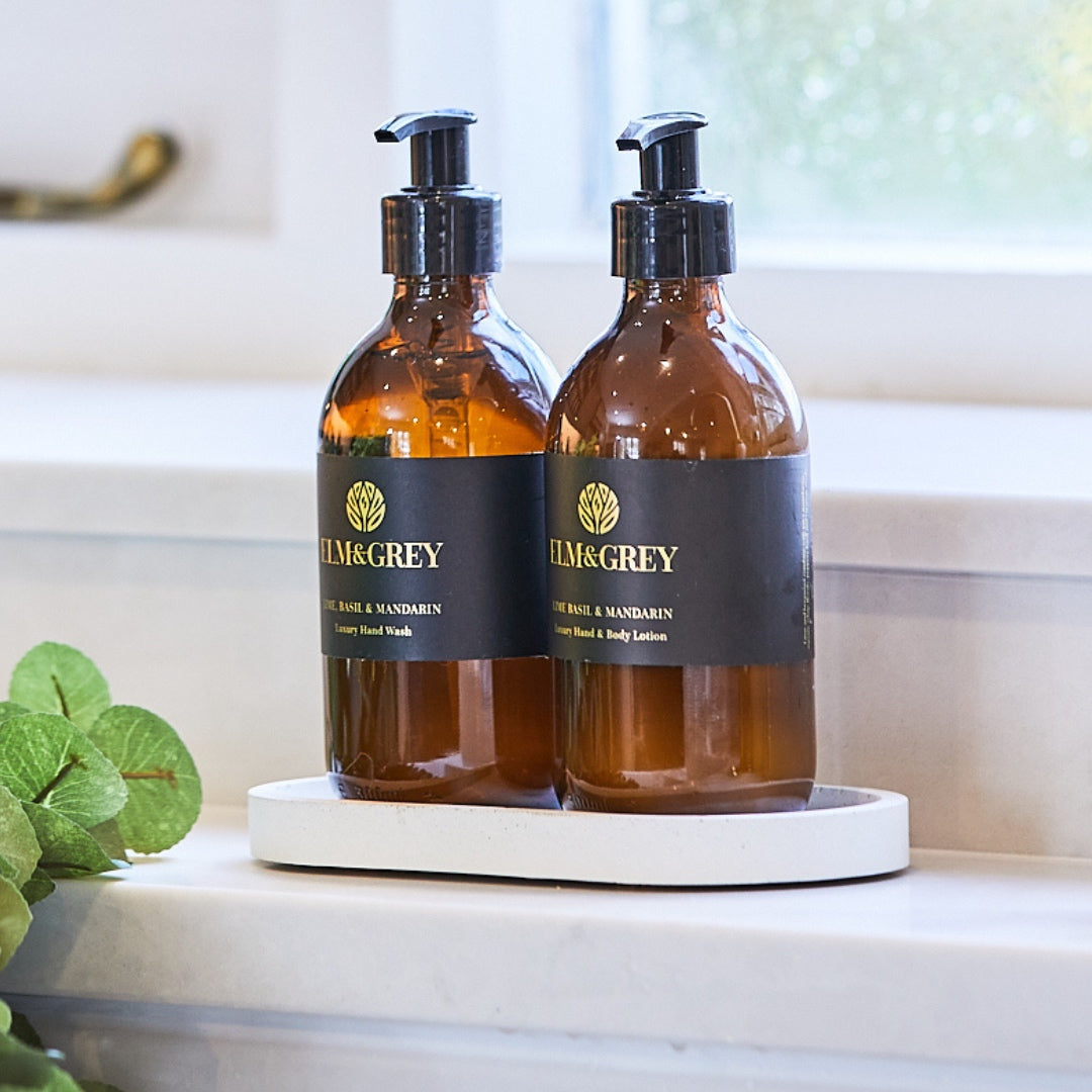 Two bottles of Elm & Grey hand wash and lotion on a white tray with a blurred background.