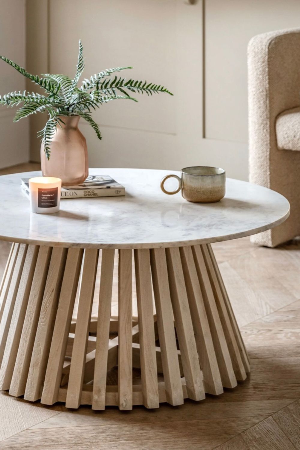 Round marble coffee table with wooden base in a room setting