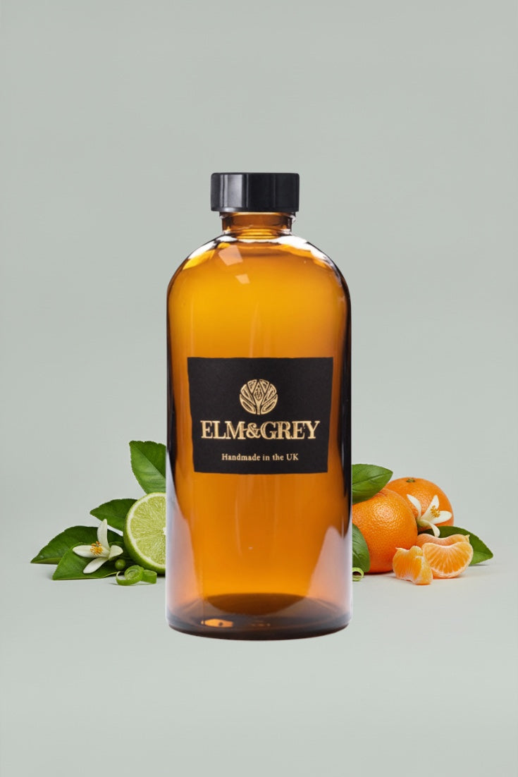 Bottle of Elm & Grey diffuser refill liquid with citrus fruits on a light gray background