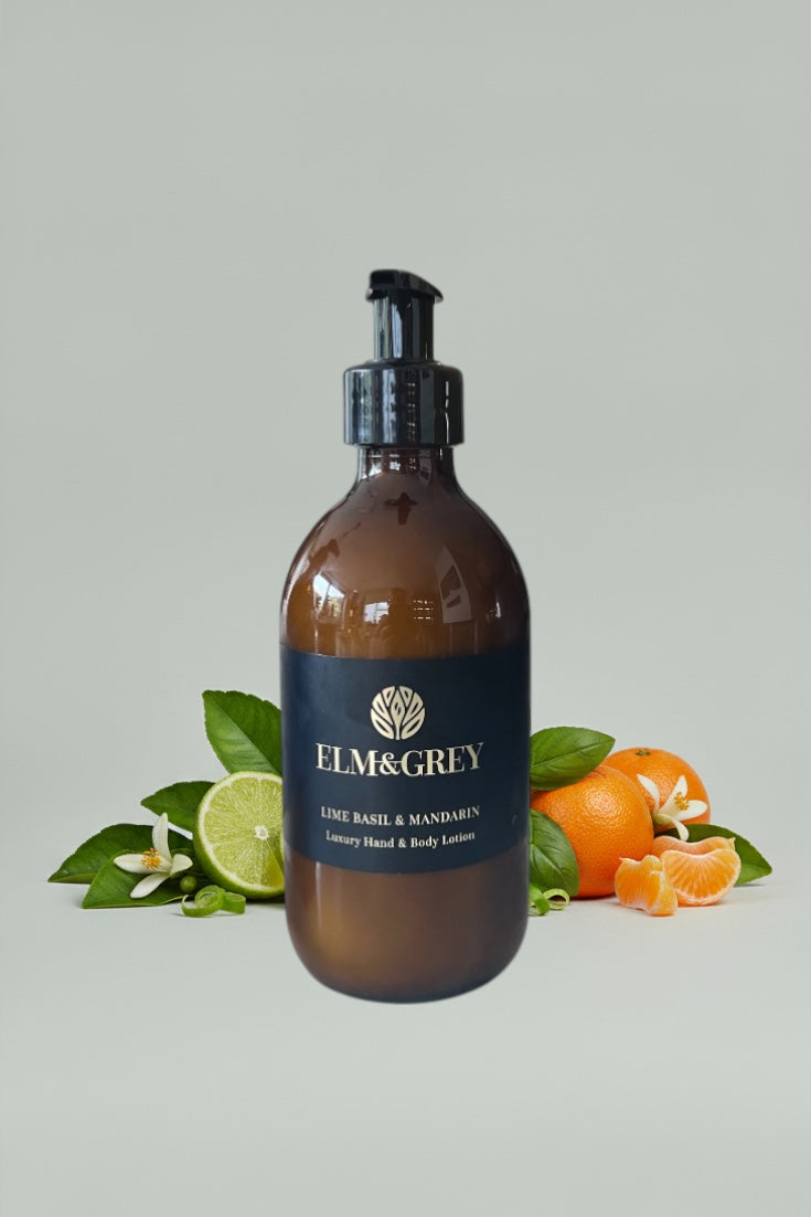 Amber bottle with black pump labeled 'ELM&Grey' surrounded by citrus fruits and leaves on a light grey background