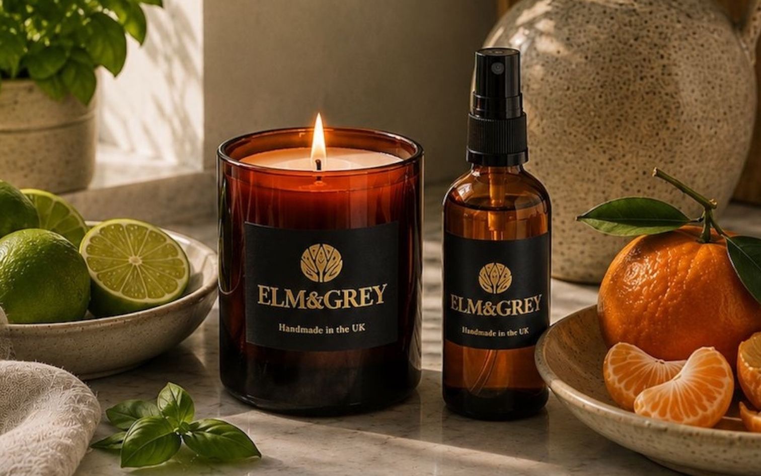 Close Up Review Image of an Elm & Grey Lime Basil and Mandarin scented candle and room spray on marble surface styled with fresh lime, mandarin and basil