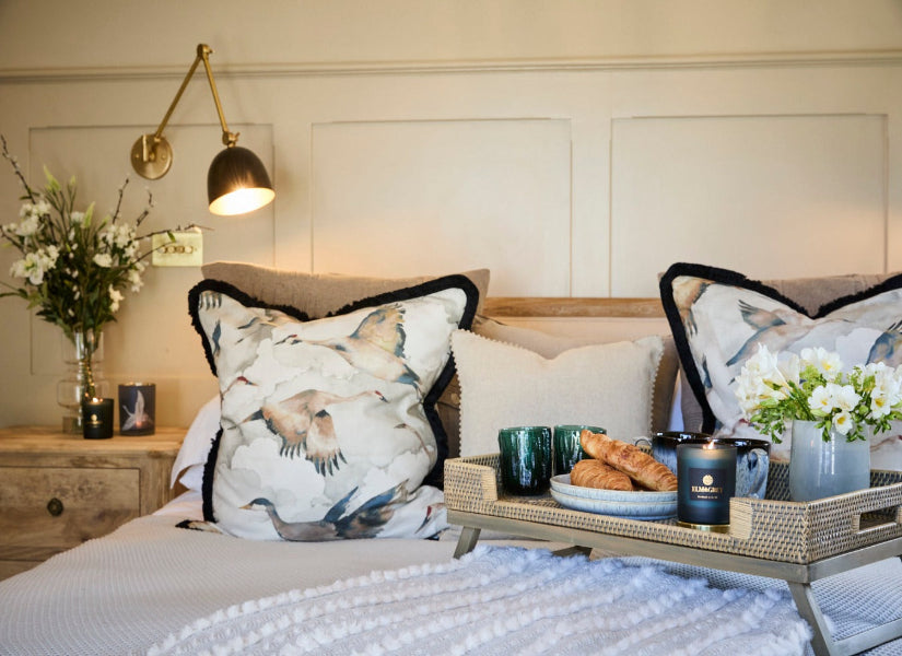 Breakfast Tray on a bed containing a lit candle and crane cushions