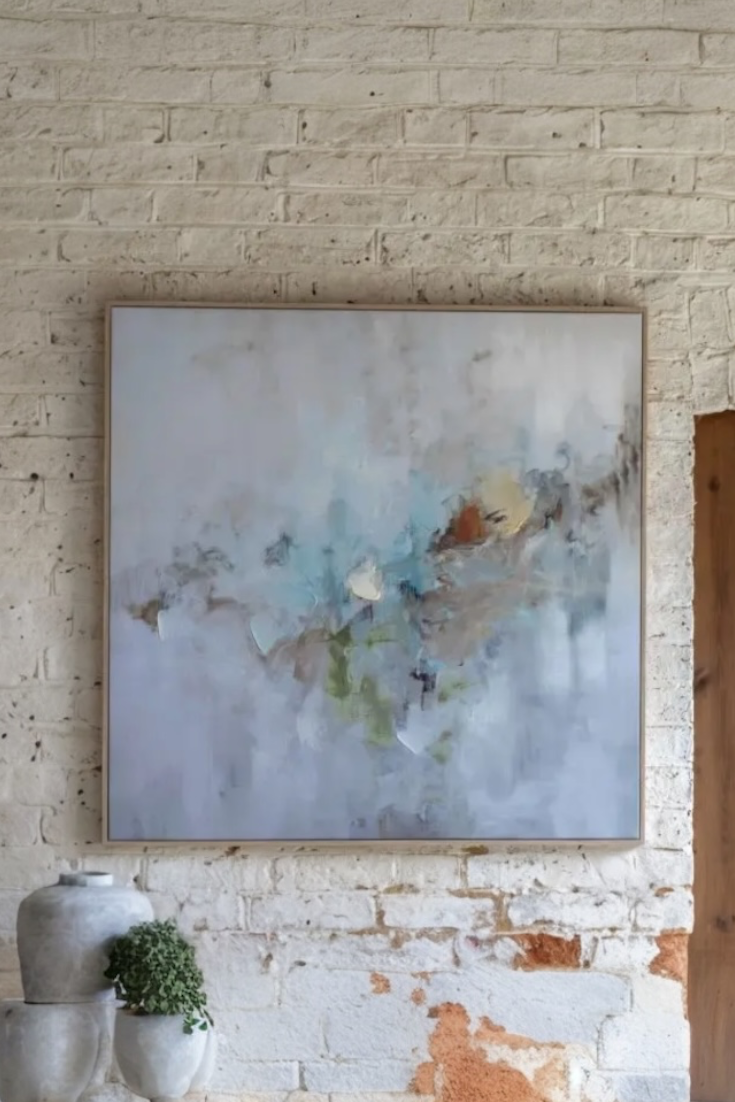 Abstract painting on a brick wall with a plant and vase in the foreground