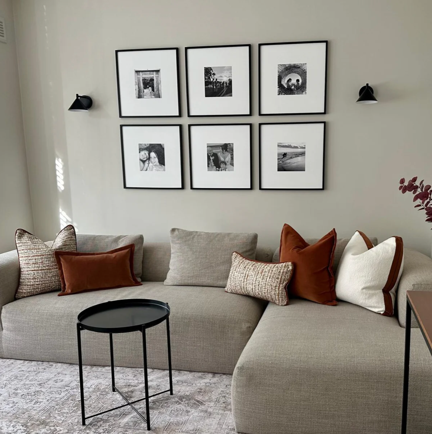 Living room with a gray sectional sofa, decorative pillows, and framed photos on the wall.
