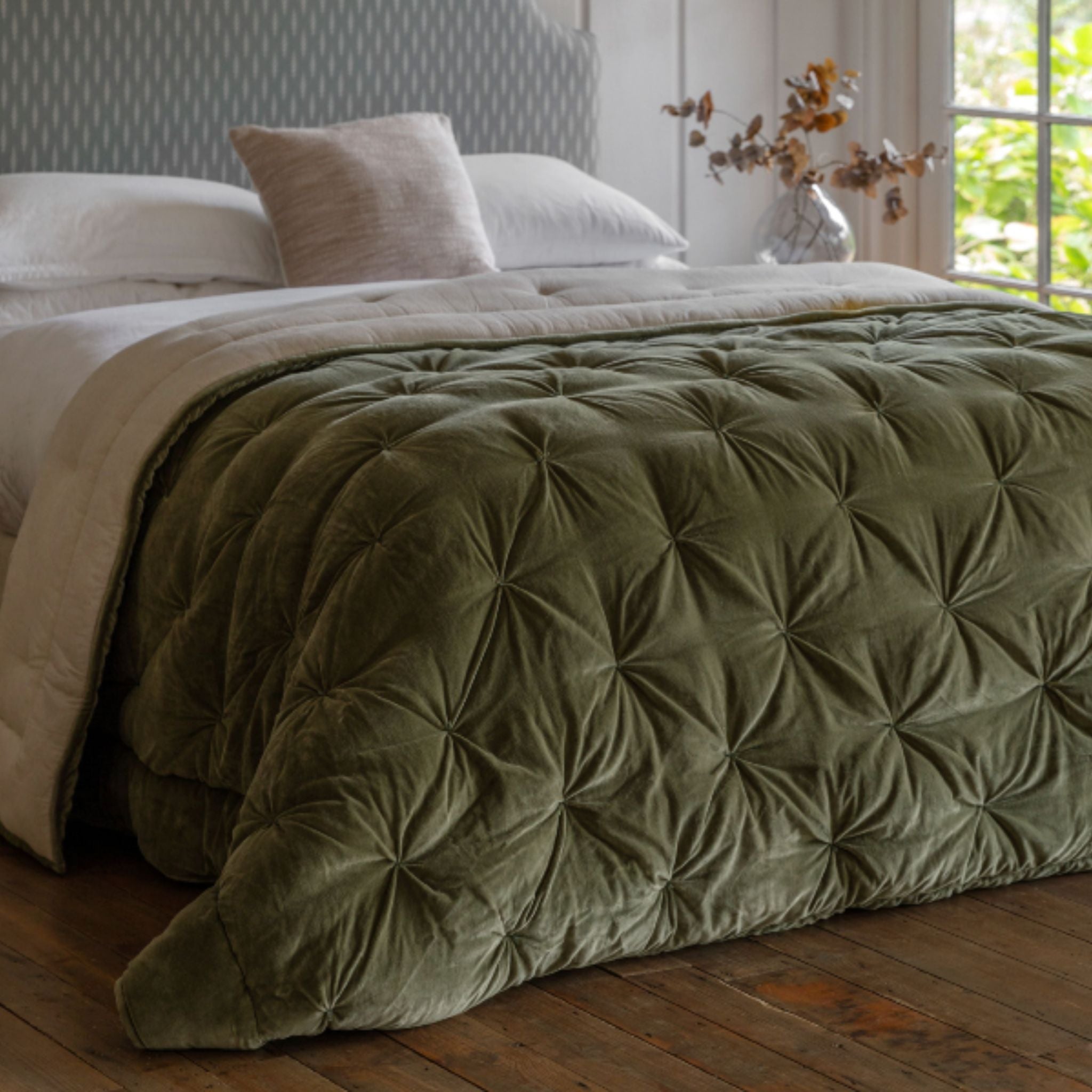 Green textured comforter on a bed in a bedroom with natural light