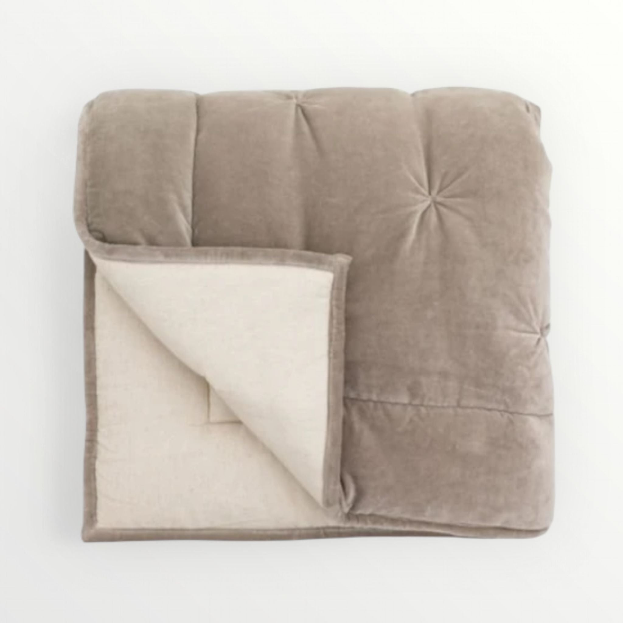 Folded beige blanket with white lining on a light grey background
