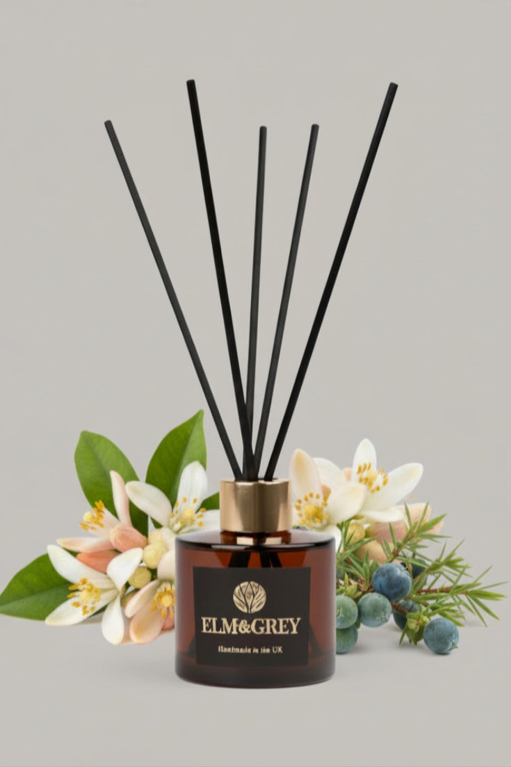 Reed diffuser with black sticks and floral decorations on a grey background