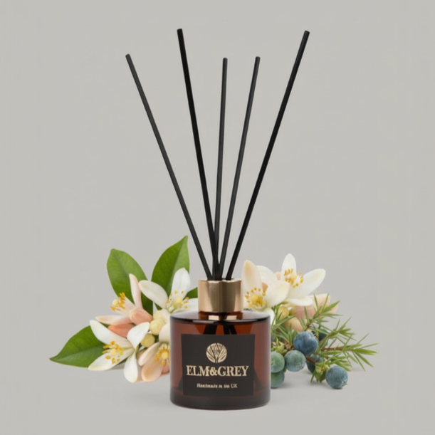 Reed diffuser with black sticks and floral elements on a gray background