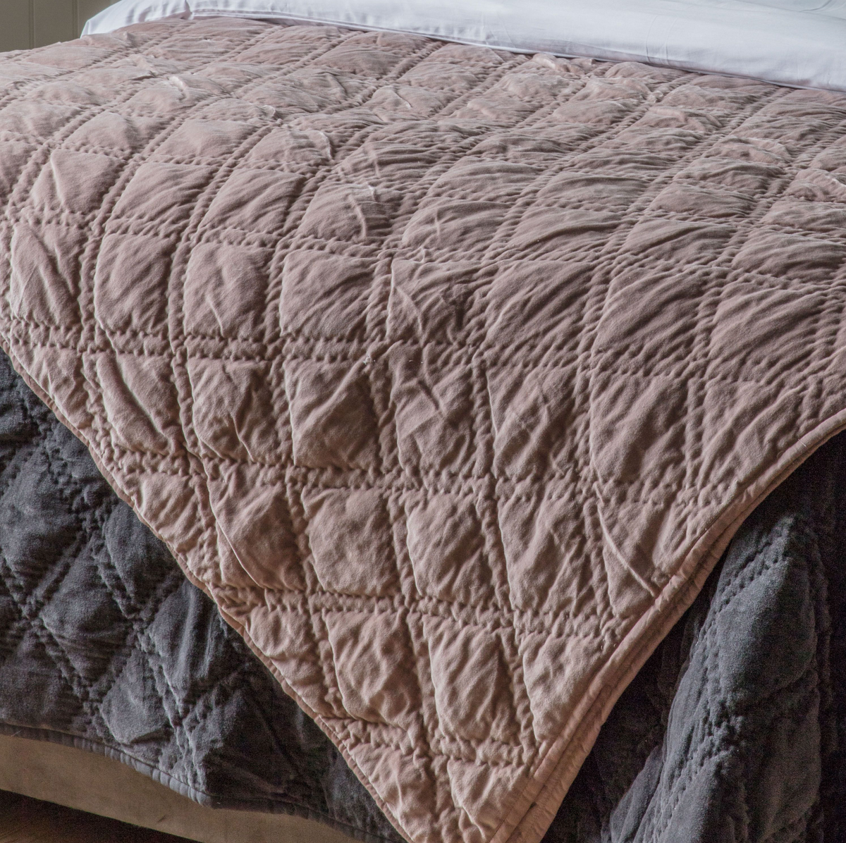 Quilted brown blanket on a bed with a grey blanket underneath
