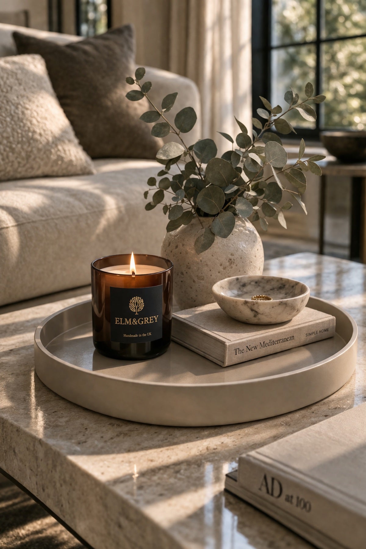 Elm ann Grey candle on a lacqured tray with books and a plant on a coffee table in a relaxing neutral coloured living room
