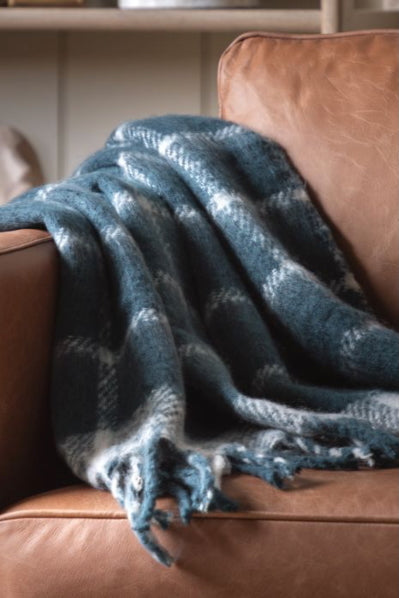 Blue plaid blanket draped over a brown leather couch