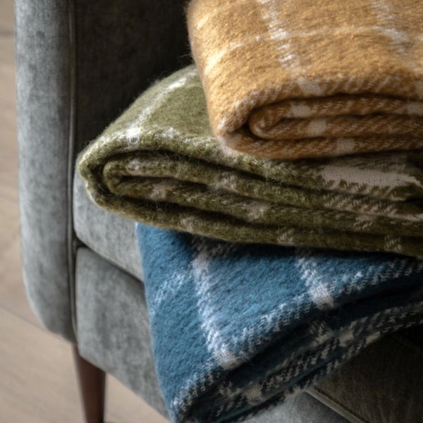 Stack of folded blankets in green, brown, and blue on a chair.
