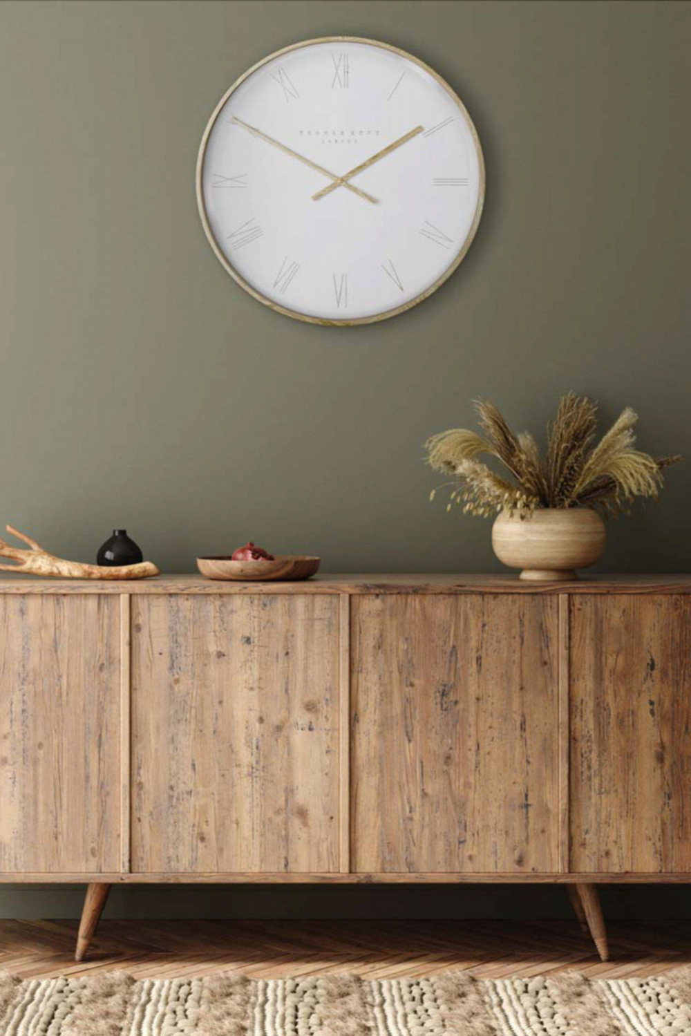 Wooden sideboard with decorative items against a green wall with a clock.