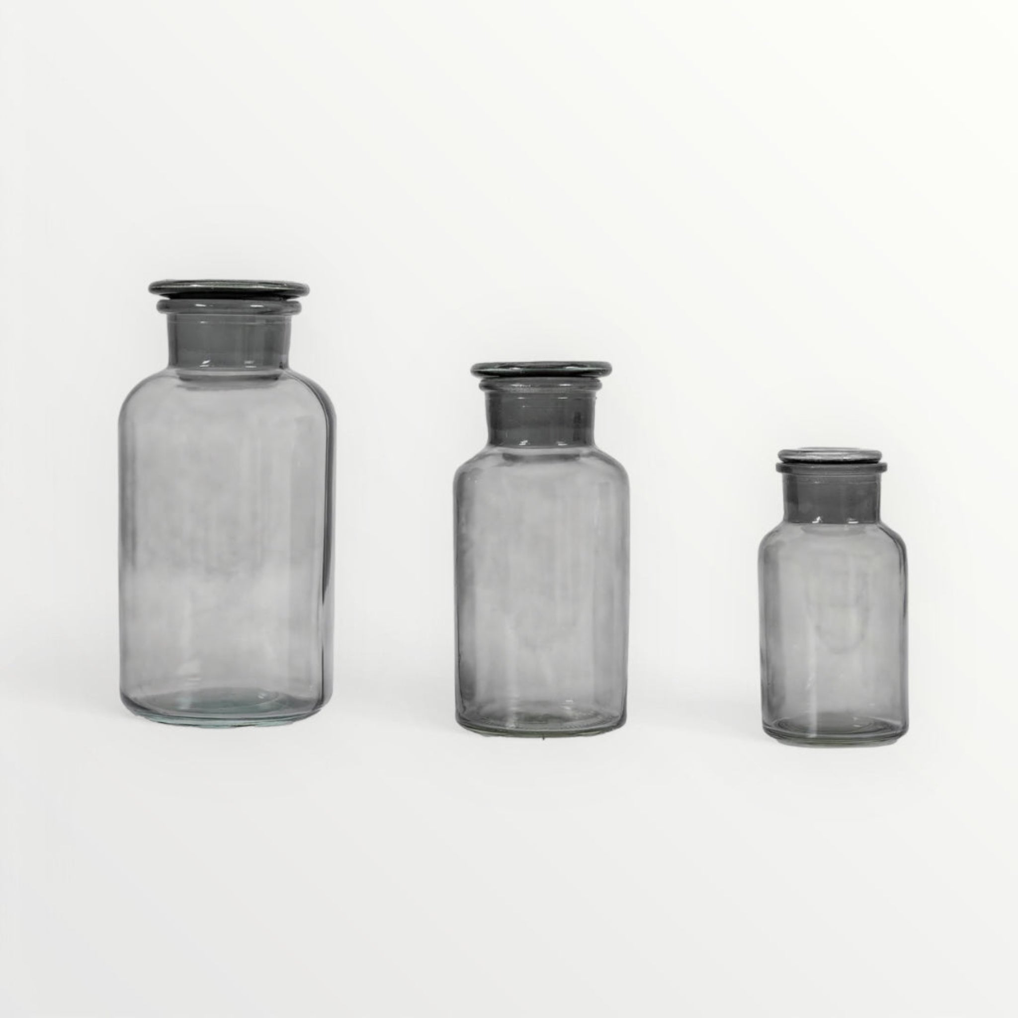 Three gray glass jars with black lids on a white background