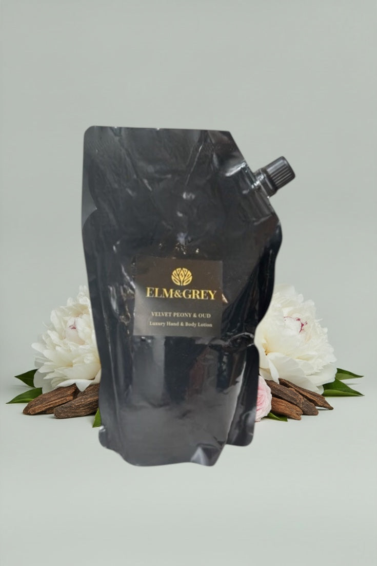 Black refill pouch with 'Elm & Grey' branding on a light grey background with white flowers and cinnamon sticks.