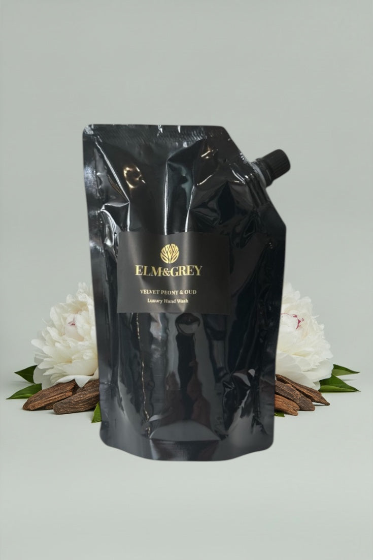 Black Elm & Grey product packaging with flowers and cinnamon sticks on a light grey background - velvet peony and oud