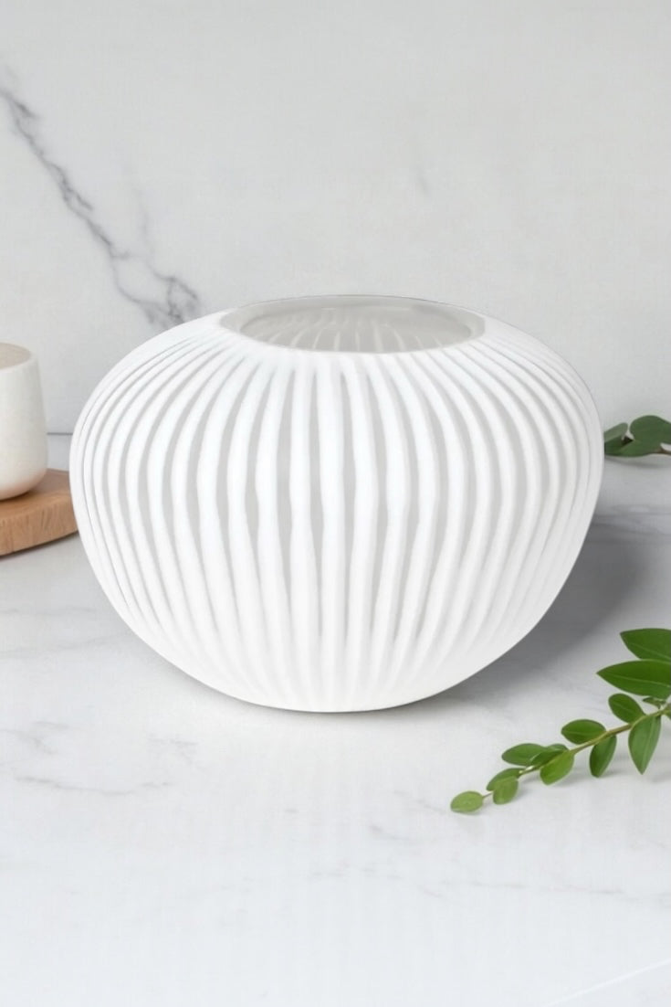 A mid-sized white sculpted glass vase with a ribbed design, standing 15cm tall and 22cm wide on a marble kitchen worktop, Elm & Grey.