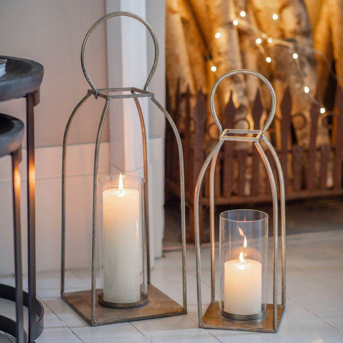 Two metal lanterns with lit pillar candles
