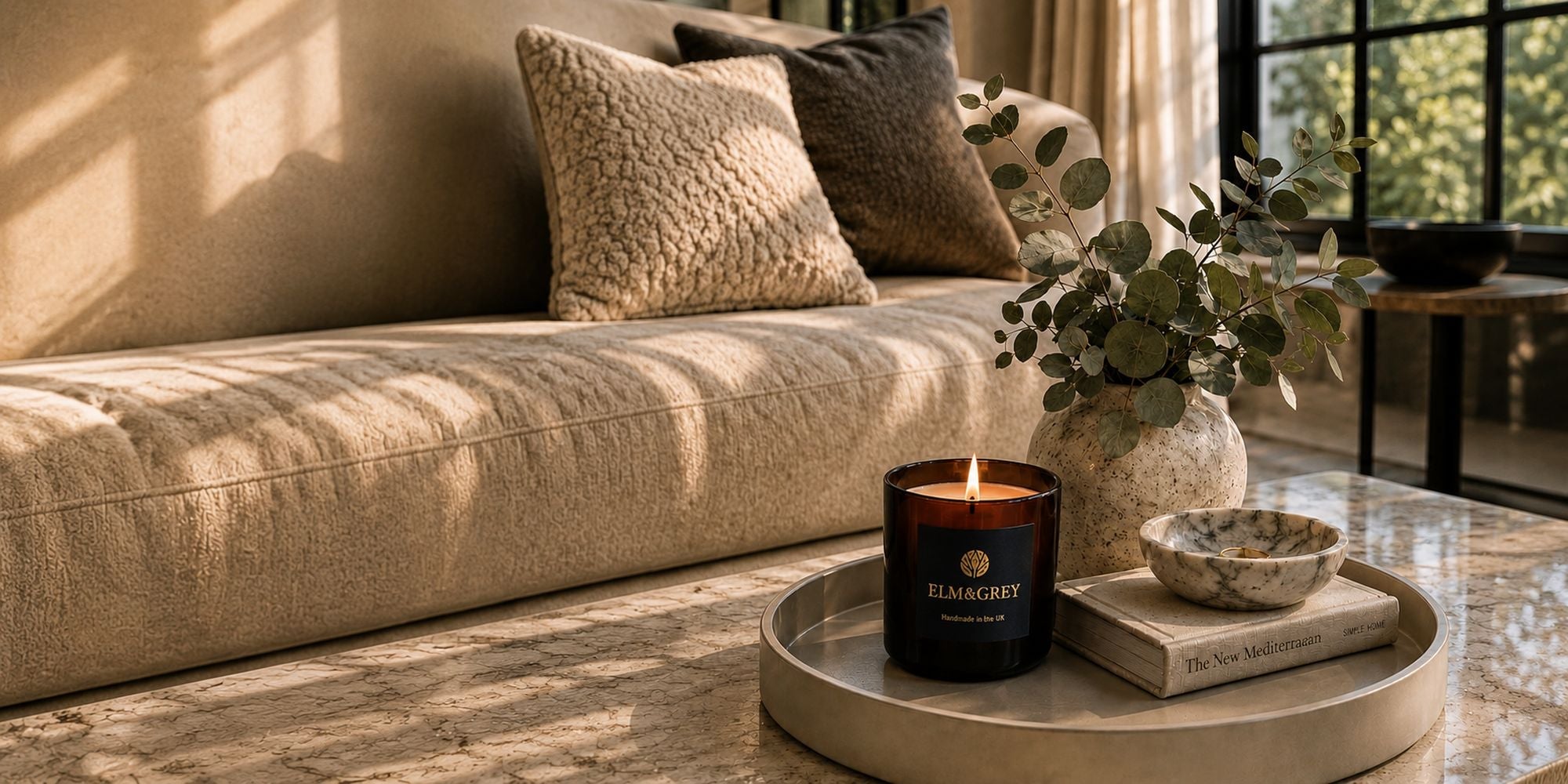 calm living room scene with an elm and grey candle lit on a tray with eucalyptus