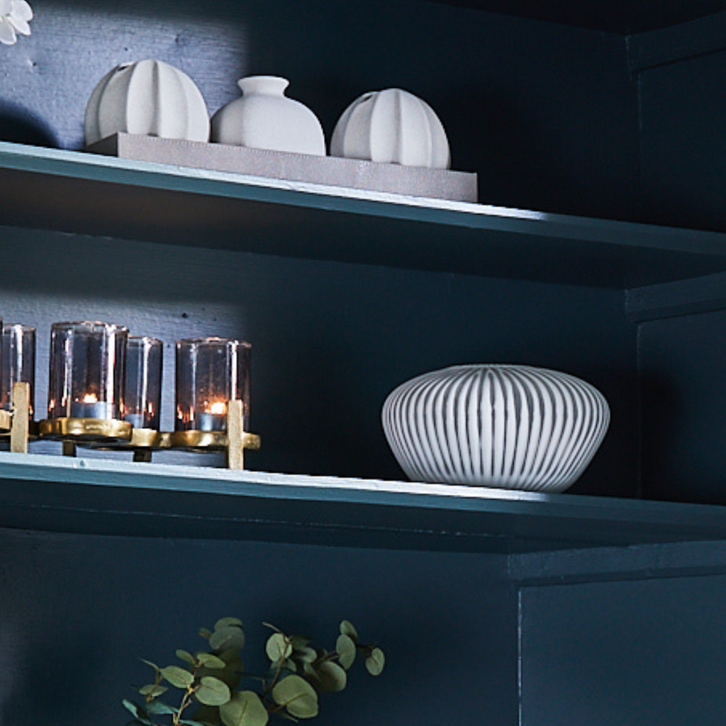 White Ribbed Vase on Shelf with lit candle holder and tray of textured vases